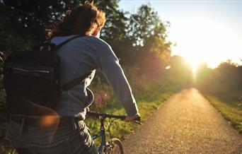 A person cycling on a cycle path at sunset