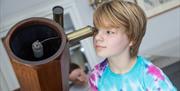 A child looking into a telescope at the Herschel Museum of Astronomy, Bath