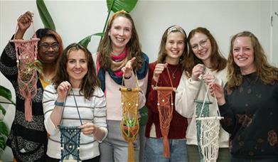A group of people holding macrame plant hangers