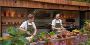 Two chefs cooking in the outdoor kitchen at the Olio Restaurant