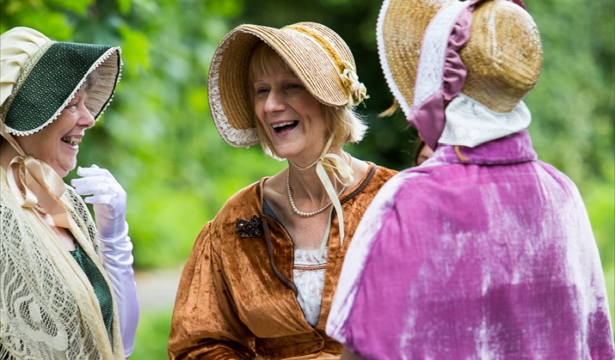 Three women dressed in Jane Austen attire.