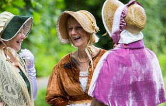 Three women dressed in Jane Austen attire.