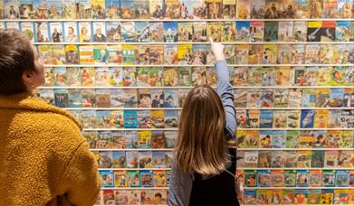 Child pointing at wall of book covers