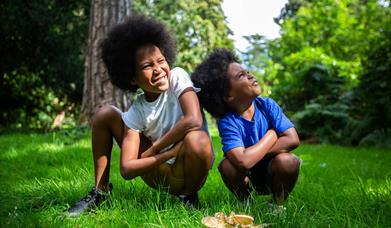 Two young boys crouching on woodland grass