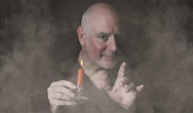 Man surrounded in smoke holding a candle stick