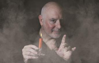 Man surrounded in smoke holding a candle stick