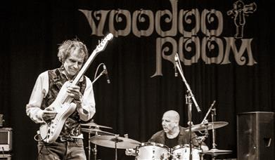 A black and white photo of Voodoo Room live on stage.